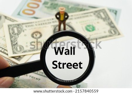 Wall Street.Magnifying glass showing the words.Background of banknotes and coins.basic concepts of finance.Business theme.Financial terms.