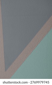 A wall with a striped pattern of gray and green, with a brown stripe in between. The wall is made of concrete and has a textured surface. The stripes are in different shades of gray and green, 