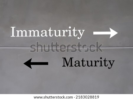 Wall with text inscription direction to opposite way MATURITY and IMMATURITY, maturity means to think and act like adult and Immaturity, on the other hand, thinks and acts like child