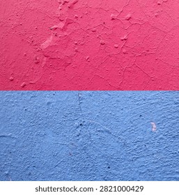 A wall texture background featuring peeling pink and blue paint, divided horizontally.
