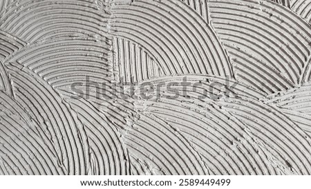 A wall with a textured, wavy pattern. The texture is created by applying a layer of plaster or cement, which gives the wall a unique and artistic appearance. The pattern is made up of various lines