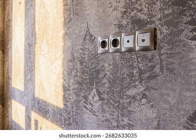 Wall with tree pattern wallpaper, sunlit, with a strip of sockets and a data port