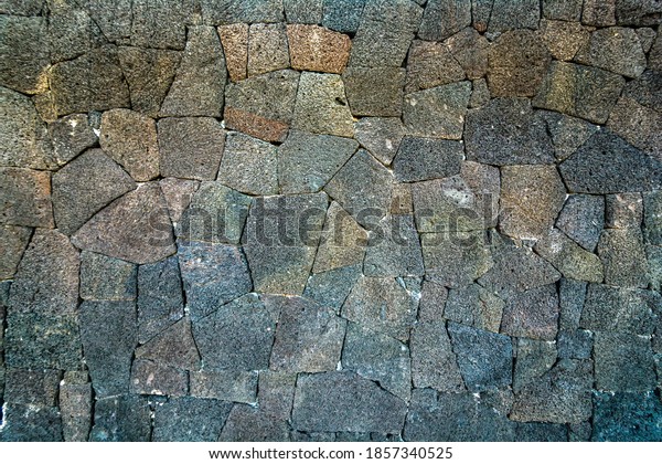 Wall of volcanic stones with grunge\
texture. Rock background lava abstract\
wallpaper.