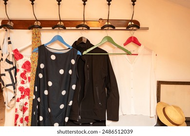 Wall wardrobe with summer dresses on colorful hangers and a straw hat next to a picture frame - Powered by Shutterstock