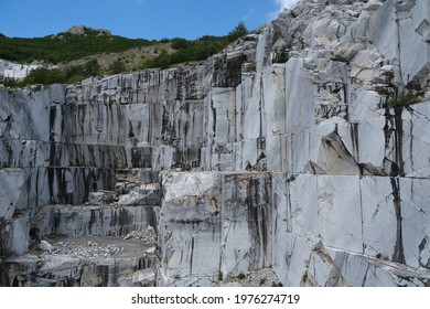 Wall of a white marble quarry under the mountain. In this area there are some quarries of white marble that is extracted from the mountain with open-air quarries. Apuan Alps, Tuscany, Italy.