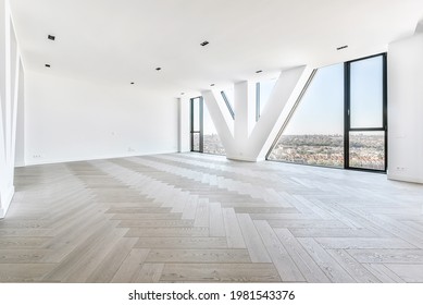 Wall windows with triangle pillar viewing cityscape from luxury penthouse apartment with parquet flooring