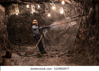 Wallace, ID / USA - August 20 2019: Tour guide in Sierra silver mine showing a demonstration of using hydraulic mining drill in the underground cave.
