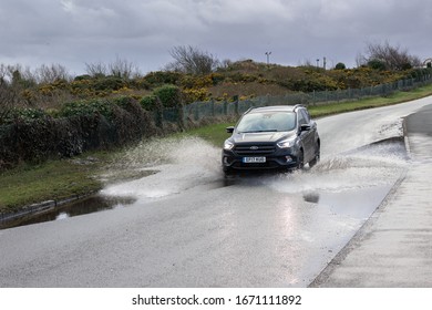 Wallasey / UK - February 25 2020: Car driving through floods after rain storms, Bayview Drive, Wallasey
