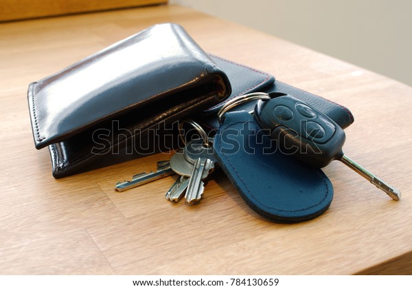 Wallet, car key, house keys and mobile phone on a table\
together in such a way that looks like someone is about to leave or\
has just arrived. 