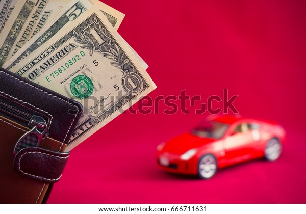 Wallet with dollars banknotes and blurred red\
car on background