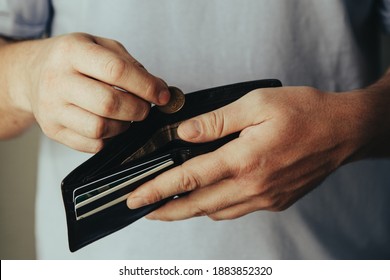 wallet in the hands of a bankrupt man. hand puts one coin. Poverty concept, crisis.