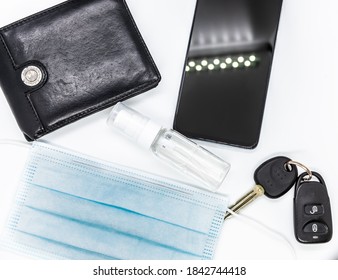 Wallet, Smartphone, Car Key, Virus Protection Mask And Hand Sanitizer On White Background Seen From Above