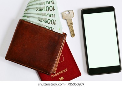 Wallet with a stack of european currency money, passport, door key and a smartphone with blank screen - mobile application for accomodation or real estate rentals and deals searching. Top view. - Powered by Shutterstock