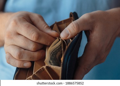 Wallet With Various Dollar Bills In The Hands Of A Bankrupt Man. Reduced Costs, Low Salary