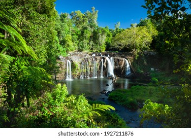 Wallicher Falls, a Wide tropical waterfall with multiple streams of water falling over a cliff surrounded by lush green rainforest, Queensland Australia.