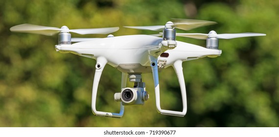 Wallisellen, Switzerland - 21 September, 2017: a Phantom 4 Pro drone in flight, green trees in the background, selective focus on the drone. Phantom 4 Pro is a drone manufactured by the DJI company.