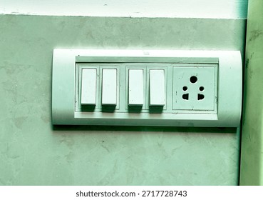 Wall-mounted electrical switchboard featuring multiple switches and a power socket, commonly used in Indian homes and offices.