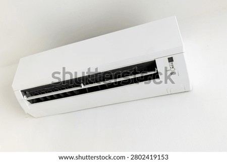 Wall-mounted split air conditioner unit on white wall, indoor climate control