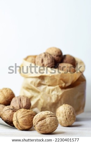 Wallnuts, full of properties, a source of protein, very healthy, in a metal shovel and behind in a kraft paper bag. Vertical shot and copy space.