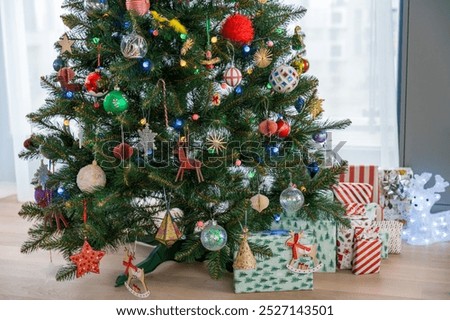 Wallpaper of artificial plastic Christmas tree with gifts, colorful decorations, lights, reindeer