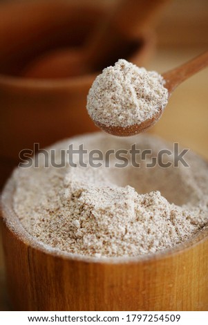 Walnut flour in a spoon on a table and in a wooden board