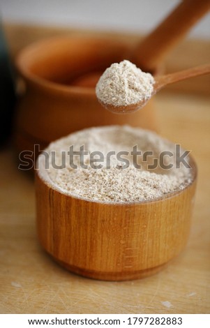 Walnut flour in a spoon on a table and in a wooden board