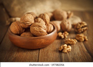 Walnut kernels and whole walnuts on rustic old wooden table