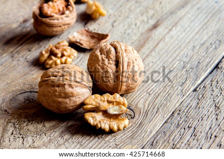 Walnut kernels and whole walnuts on rustic old wooden table with copy space