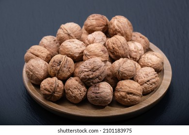 Walnut on black, copy space. Group of walnuts on a black background. Nuts on a wooden plate.