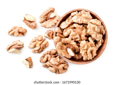 Walnut peeled in a wooden plate and scattered on a white background. The view fromtop.