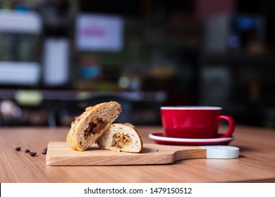 Walnut wheat bread with a cup of hot coffee in the red mug on top of cutting board