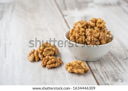 Walnut in the white bowl on lignt wood table with copy space. Stock photo, commercial banner template.