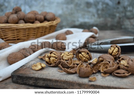 Walnuts in a basket, nutshells and kernels on a rustic board.