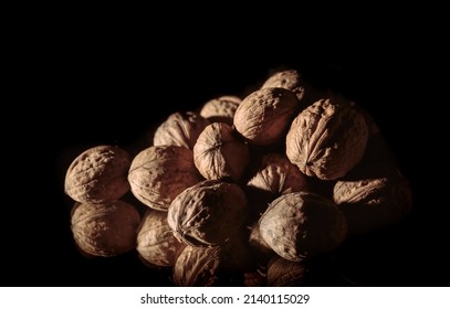 A Walnuts Heap Close-up. Copy Space. Beautiful Still Life On A Dark Background. Healthy Food. Ingredient. Useful Brain Nutrients. Nut Is A Tasty Diet Snack. Brown Color. Wallpaper. Photo Art. Banner.