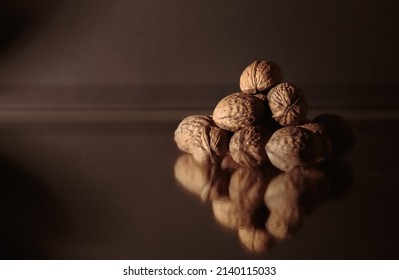 The Walnuts Heap Close-up. Copy Space. Beautiful Dark Background With Healthy Food. Ingredient. Useful Brain Nutrients. Nut Is A Tasty Diet Snack. Macro. Brown Color. Wallpaper. Photo Art Still Life.