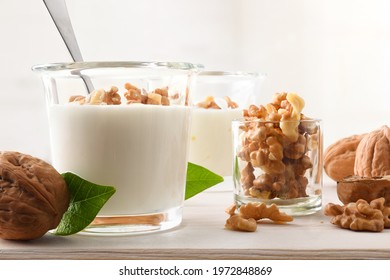 Walnuts Pieces On Natural Yogurt With Walnuts And Bowl With Walnuts On Wooden Kitchen Bench. Front View.