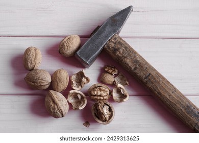 Walnuts, whole and peeled, on a pink wooden background next to a hummer.  - Powered by Shutterstock