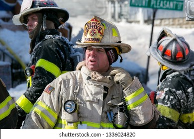 Waltham, Massachusetts / USA - February 16 2015: Deputy Fire Chief Coated In Ice Commands Firefighting Operations At An Early Morning House Fire During Frigid Winter Temperatures 