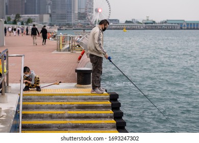 Wan Chai/Hong Kong - Apr 4 2020: Mask-wearing Father And Son Fishing On The Dock