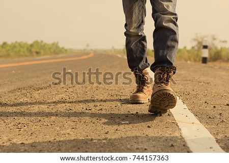 Wanderer or loner walking down an empty road and hot. Road hitch-hiking.