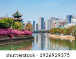 Wangjiang Pavilion during Spring with peach blossoms in Chengdu, Sichuan, China, overlooking the Jinjiang River with residential and office buildings in the background