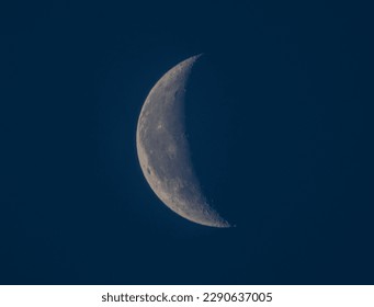 The waning crescent moon hangs low in the sky, its graceful arc a reminder of the fleeting nature of time. Its dim light casts a hazy glow, creating an aura of peacefulness and introspection.
