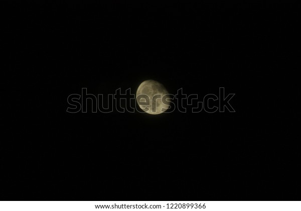 Waning Gibbous,\
Partially Lit Warm Colored Moon at Night with Craters and Seas\
Visible in a Pure Black\
Sky
