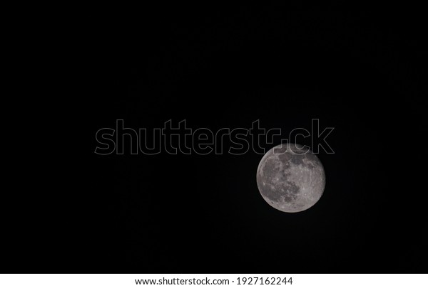 Waning moon on a dark sky. Moon\
with craters. Textured circles in three trend colors: blue sky,\
black, beige. Hand paint texture, isolate on a white\
background.