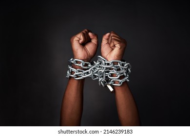 I want to break free. Cropped shot of a mans hands tied up with chains against a black background.