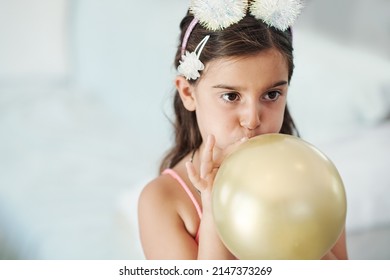 I want to see how big it gets. Shot of an adorable little girl blowing up a balloon at her birthday party.