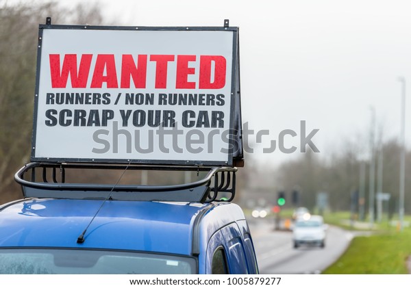 Wanted Runners Non Runners Scrap Your Car sign\
on car roof next to UK\
motorway