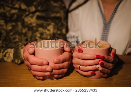 War and love. Military husband came back from army. First meeting after long separation. Closeup husband in camouflage uniform with woman drinking coffee and finally together. Serviceman goodbyes.