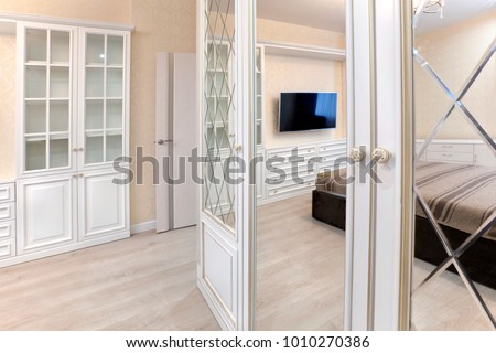 Wardrobe in the bedroom with a mirror smooth and with a bevel. Interior with contrast of light and dark
