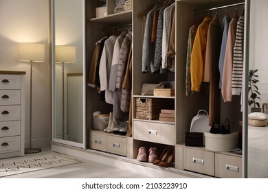 Wardrobe closet with different stylish clothes, shoes and home stuff in room - Powered by Shutterstock